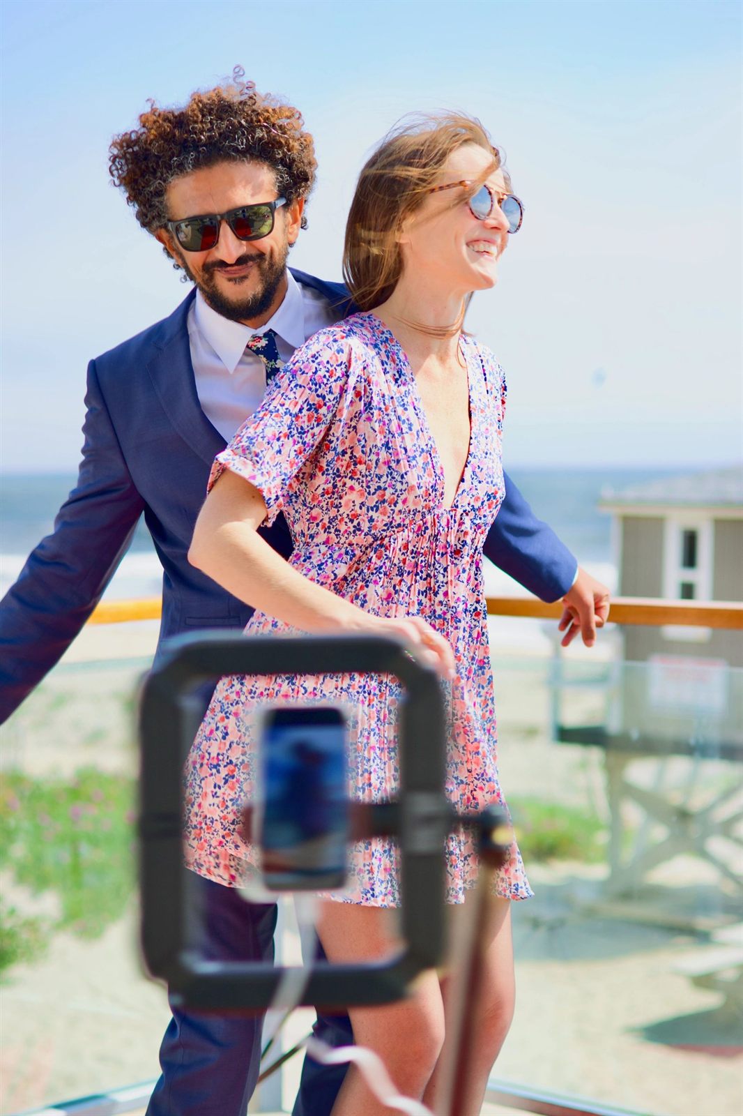 Smiling couple in sunglasses posing on the 360 booth in front of the ring light camera